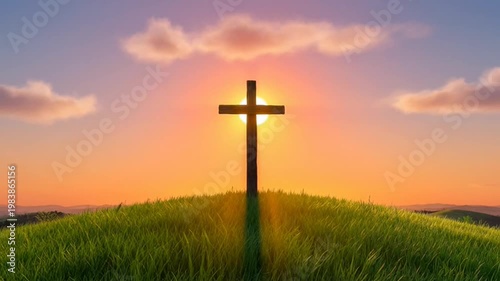 Cross at Sunset: A solitary cross stands silhouetted against a radiant sunset sky, evoking feelings of faith, hope, and spiritual tranquility. The cross is on a green hill with an orange sky.