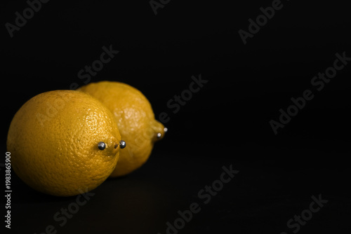 Bild auf Leinwand Fresh lemons with nipple piercing on dark background