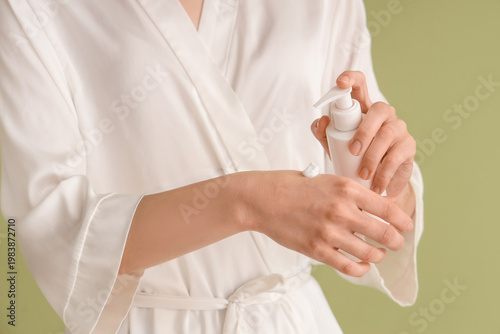 Woman in bathrobe applying ...