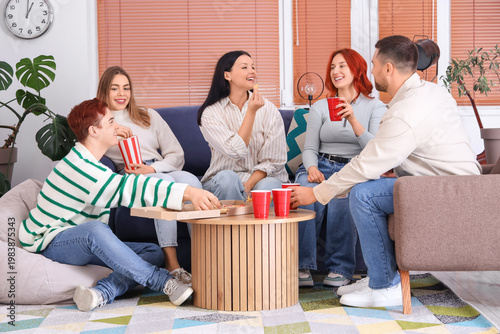Group of young friends with beer and snacks resting at home