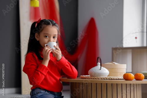 Cute little Asian girl drin...
