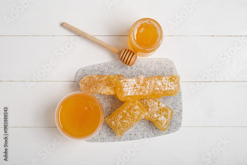 Board with sweet honey, dipper and combs on light wooden background