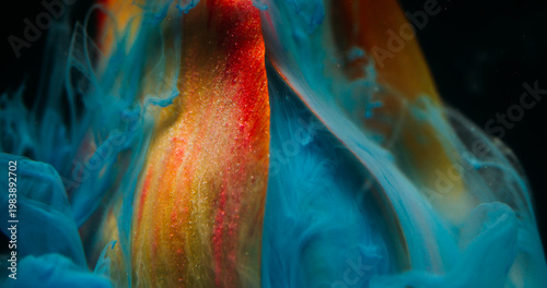 Fog flower. Ethereal smoke. Defocused yellow red color tulip plant nature blue ink flowing in water on abstract dark black background.