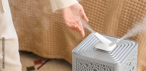 Bild auf Leinwand Woman with modern air humidifier in bedroom, closeup