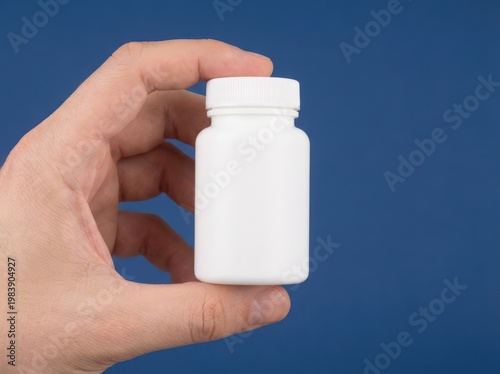 Hand holding a white pill bottle on a blue background