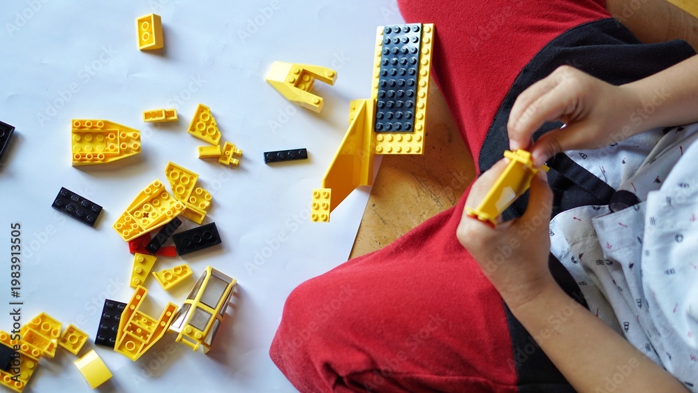 Fototapeta premium Close up of child's hands playing with colorful plastic bricks or lego. Toddler having fun and building out of bright constructor bricks. Development toys