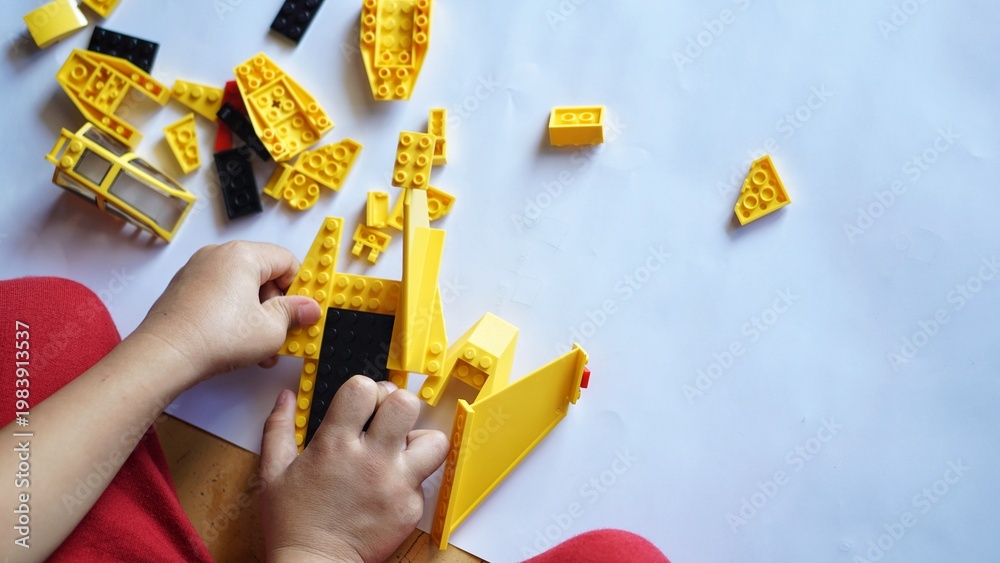 Fototapeta premium Close up of child's hands playing with colorful plastic bricks or lego. Toddler having fun and building out of bright constructor bricks. Development toys