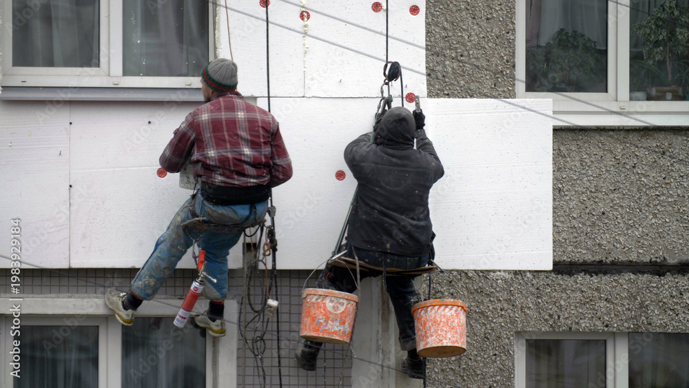 Fototapeta premium climbers work on the building, climbers are working on the insulation of facades of a multi-storey residential building