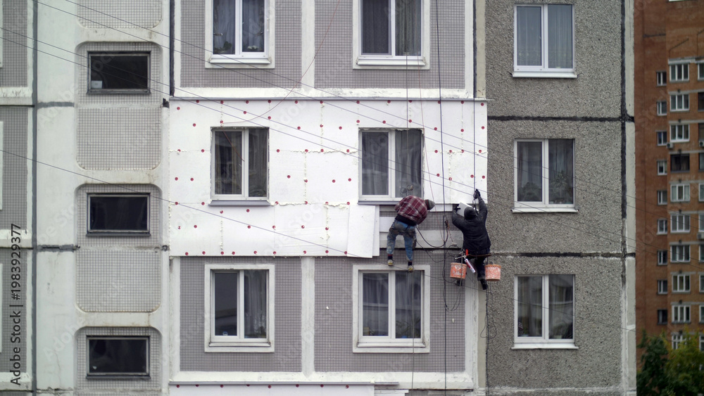 Fototapeta premium climbers work on the building, climbers are working on the insulation of facades of a multi-storey residential building