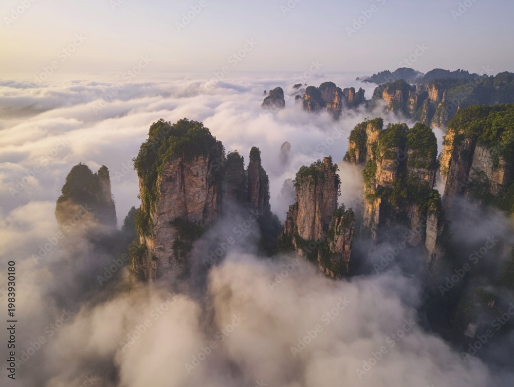 Fototapeta premium Chinese mountains rising above clouds with mist and sunlight, dramatic natural landscape with stone peaks and serene travel scenery.
