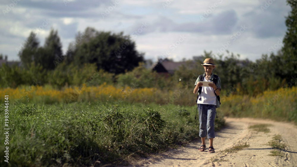 Obraz premium happy boy traveler in a hat walking and using a tablet, outdoors, have fun and enjoy