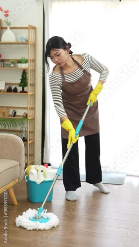 Within the household realm, a woman with mop indulges in effective cleaning, mopping floor. Maid provides a meticulous home service, showcasing commitment to maintaining a pristine house.