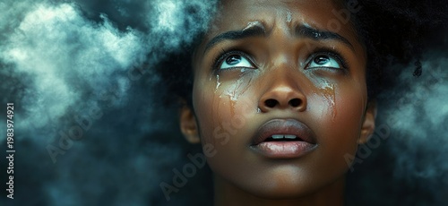 Close-up portrait of a young woman with curly hair and glistening tear streaks, looking upward through swirling mist with a sorrowful, longing expression