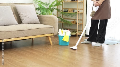 Within the household realm, a woman with mop indulges in effective cleaning, mopping floor. Maid provides a meticulous home service, showcasing commitment to maintaining a pristine house.