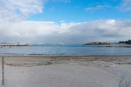 Coastal landscape of the Vigo estuary with the Canido pier and the Cies Islands under a bright blue sky today