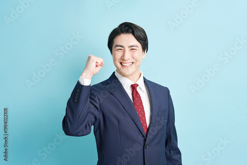 ガッツポーズする若手ビジネスマン 水色背景