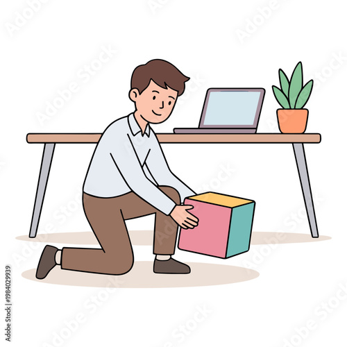 Man kneeling down to move colorful box under office desk with laptop