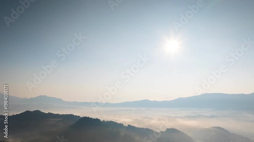 Hyperlapse by dorne Spectacular aerial view of a sea of mist covering mountain ranges under a bright mornig sun. Captures peaceful nature, morning fog, and scenic horizons at sunrise.