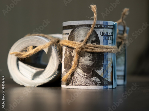 Bundles of cash tied with twine placed on a dark surface in a room at an unspecified time of day