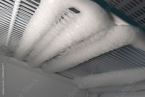 Ice buildup on refrigerator coils in a home kitchen during winter months