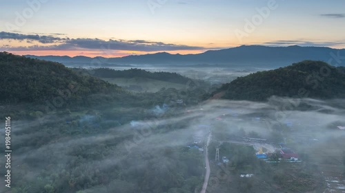 Aerial photograph of mountainous landscapes and villages in northern Thailand, shrouded in mist and morning light in Lampang Province, Thailand.