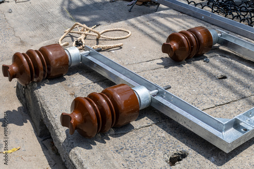 Schilderij op canvas Three brown ceramic insulators on a metal frame lie on concrete, ready for use in electrical infrastructure maintenance and wire replacement in Thailand