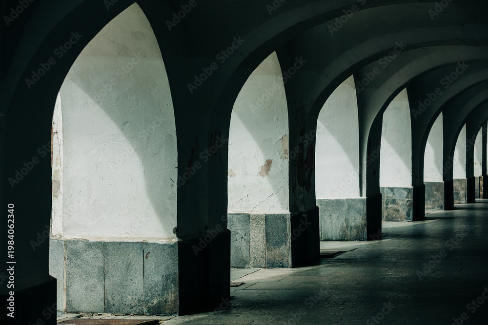Naklejka premium Nineteenth-century arcade under houses for pedestrian passage, shadow, old town, Europe