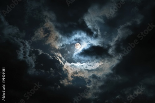 Mysterious full moon glowing through dark stormy clouds, dramatic night sky