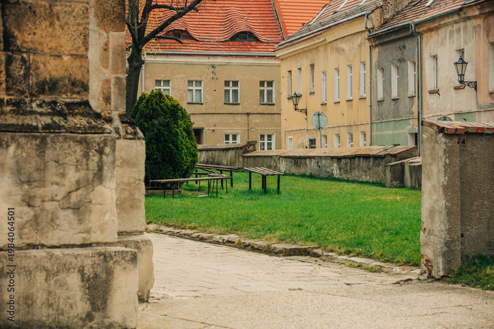 Naklejka premium 19th century European Catholic church inner courtyard with grass, stone, facade, Poland