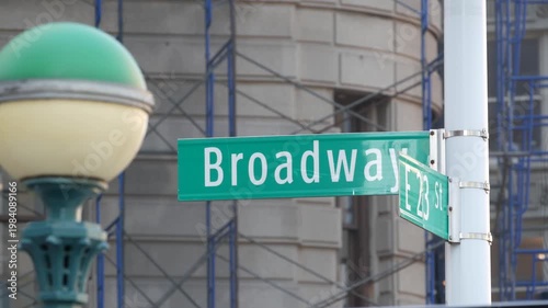 New York City Broadway street sign in Manhattan Midtown, United States. Urban road sign, traffic sign. Building architecture in Flatiron district. Crossroad with 5 fifth avenue. Subway metro globe.