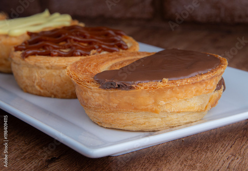 Reposteria casera, pan de hojaldre sobre un plato blanco para disfrutar en familia con cafe o leche. cubierta de chocolate, macro