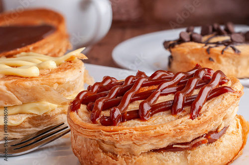Reposteria casera, pan de hojaldre sobre un plato blanco para disfrutar en familia con cafe o leche, relleno de cajeta con taza de cafe al fondo