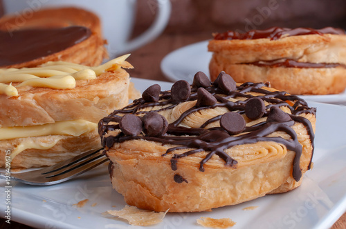 Reposteria casera, pan de hojaldre sobre un plato blanco para disfrutar en familia con cafe o leche cubierta de chocolate oscuro con chispas de chocolate