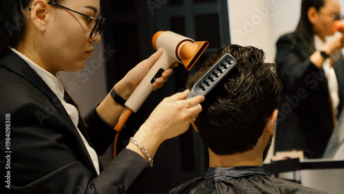 Foto Professional barber drying hair and styling for young male client