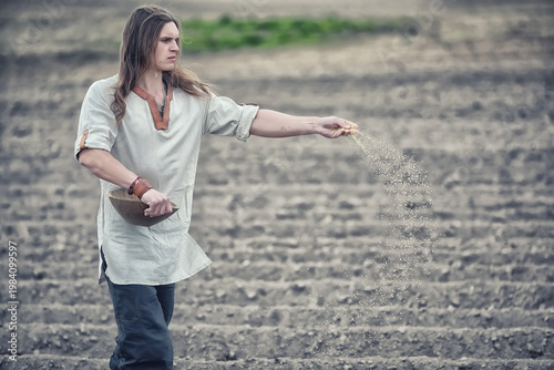 Fotografie A young peasant sows the field with grain