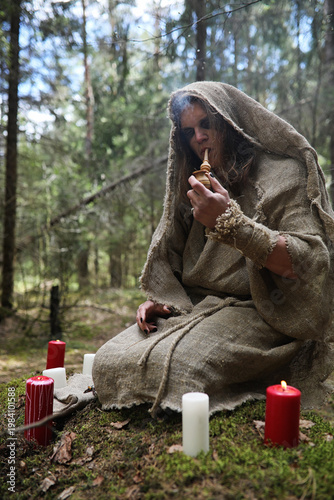Fotografie A man in a cassock spends a ritual in a dark forest
