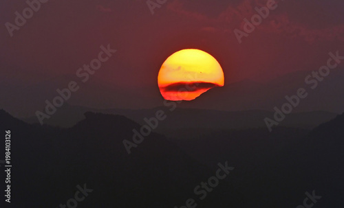 an eerie sunset, with sun spots,  over the colorado rocky mountains through the smoke of the western forest fires , as seen from broomfield