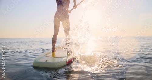 A happy young woman walking on a sup board by the sea during her summer vacation. Slow motion