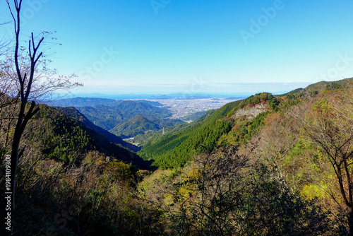 Panoramic mountain view on Shikoku Henro overlooking valley and distant coastline under clear blue sky in Japan