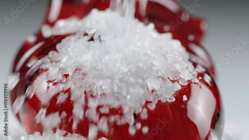 Sea salt crystal coarse salt red pepper macro seasoning closeup, heart on red glass texture with falling grains, kitchen food spice concept