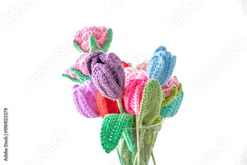 Colorful knitted flowers in a vase against a white background. Handmade idea concept. Leisure time, hobby activity. Wool knitting flowers. Copy space, blank, empty. No people, nobody. 