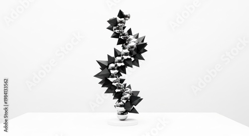 A black and white abstract sculpture featuring a series of interconnected spheres and pyramids, set against a plain white background.
