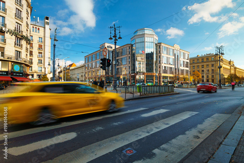 Fotografie Fast moving yellow taxi on the road in Budapest with architectural buildings background