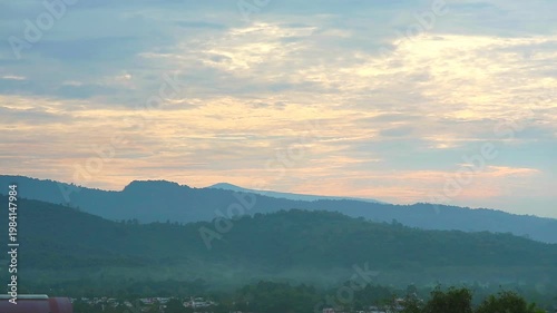 Serene Morning Landscape with Misty Mountains and Soft Clouds Under a Colorful Sky