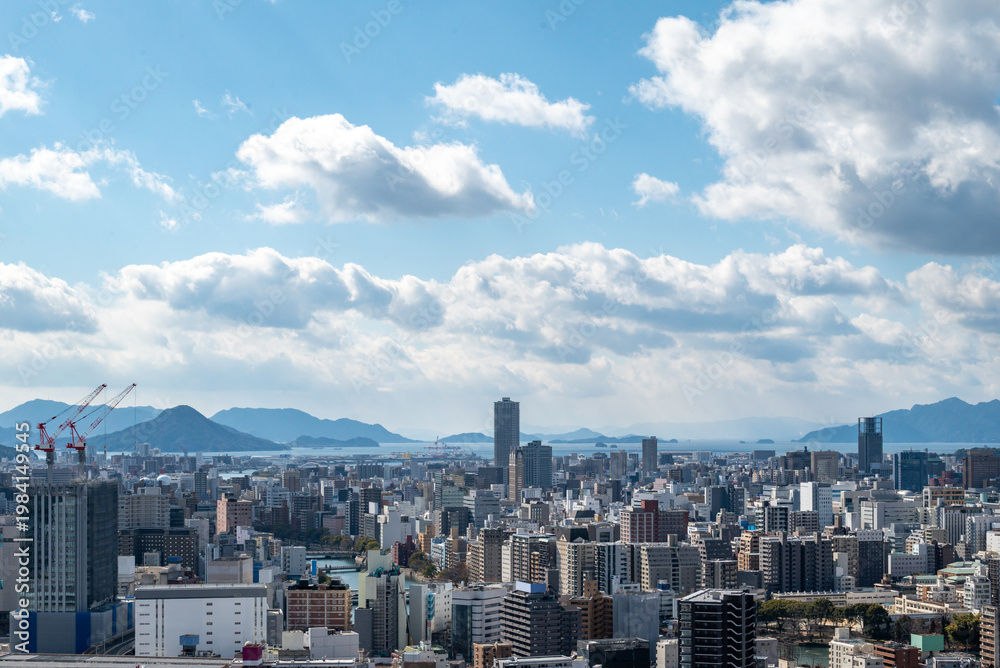 Obraz premium Panoramic View of Hiroshima Cityscape with Skyscrapers and Seto Inland Sea under a Blue Sky