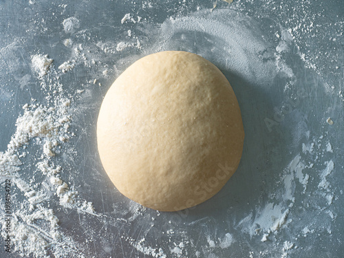 top view bread dough with white wheat flour on stainless steel working surface