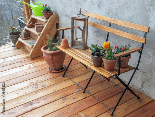 flower pots and lantern put on a wooden bench against gray wall of a wooden t...