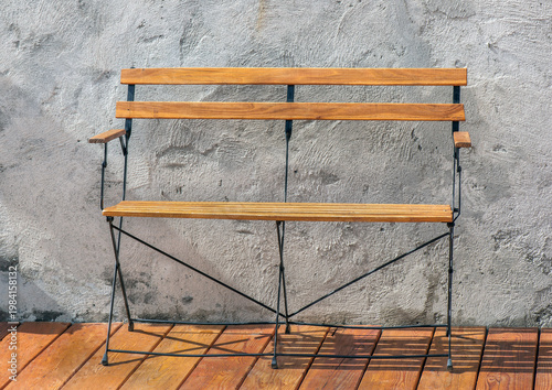 front of view on decorative bench in metal and wooden with modern style against the textured gray wall of a wooden terrace