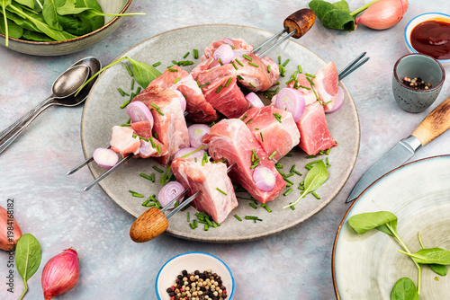 Uncooked pork kebabs with onion on skewers
