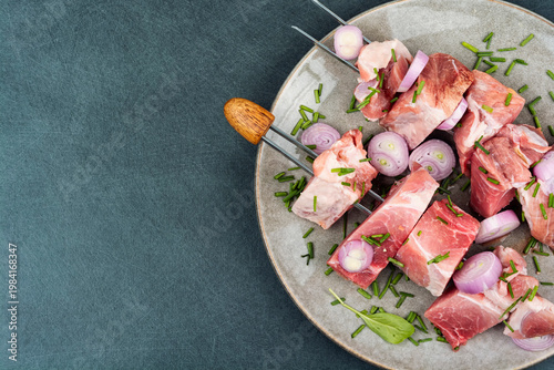 Raw pork skewers with onion and herbs on plate